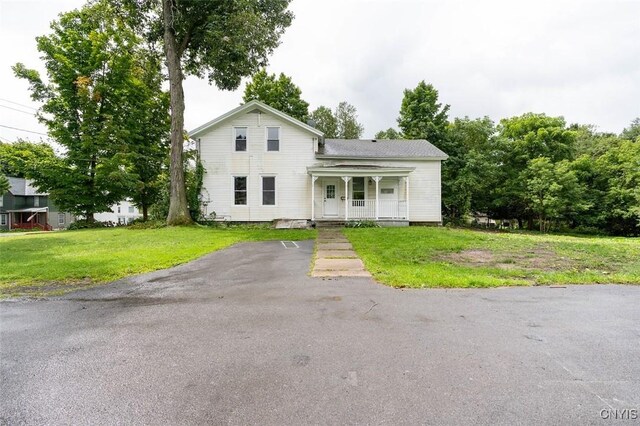 front facade with covered porch and a front yard