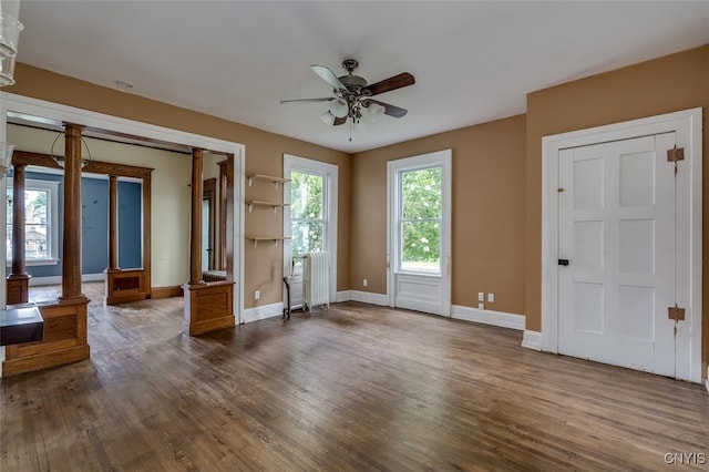 spare room with hardwood / wood-style floors, ceiling fan, and ornate columns