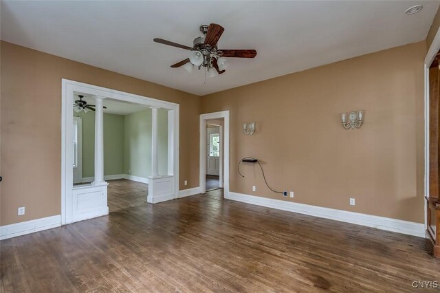 unfurnished room featuring ceiling fan, decorative columns, and dark wood-type flooring