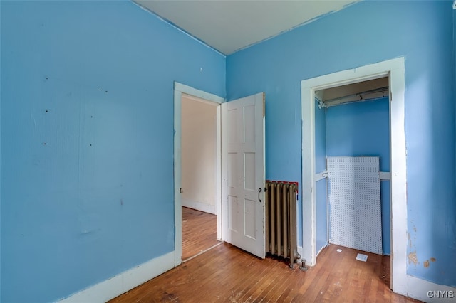 unfurnished room featuring radiator heating unit and hardwood / wood-style flooring