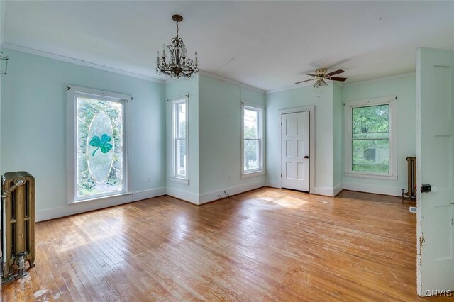 interior space with ceiling fan with notable chandelier, light hardwood / wood-style flooring, plenty of natural light, and ornamental molding