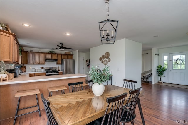 dining area with ceiling fan with notable chandelier and dark hardwood / wood-style floors