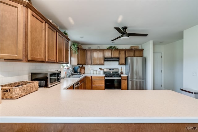 kitchen featuring stainless steel appliances, ventilation hood, tasteful backsplash, sink, and ceiling fan