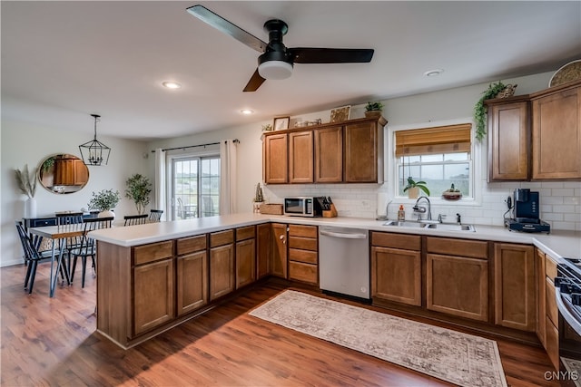 kitchen featuring decorative light fixtures, dark hardwood / wood-style floors, ceiling fan, stainless steel appliances, and kitchen peninsula