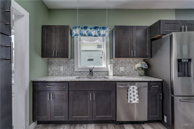 kitchen with appliances with stainless steel finishes, dark brown cabinetry, sink, tasteful backsplash, and wood-type flooring