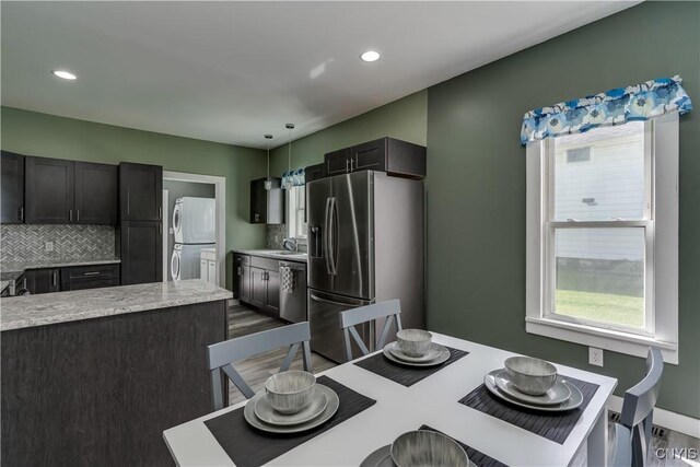 dining room with stacked washer and clothes dryer, hardwood / wood-style flooring, and sink