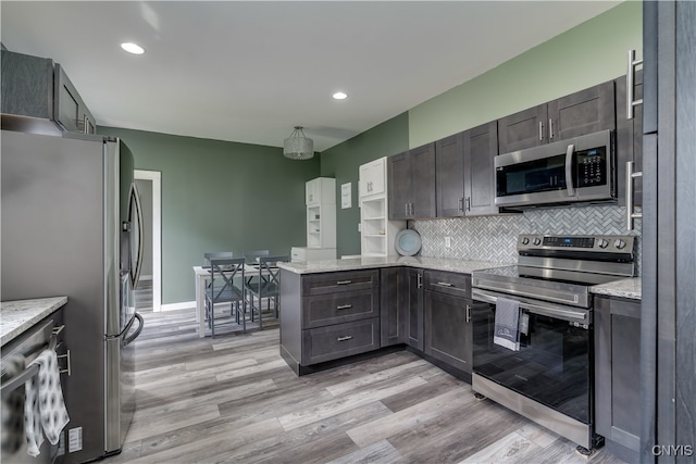 kitchen with backsplash, stainless steel appliances, kitchen peninsula, and light wood-type flooring