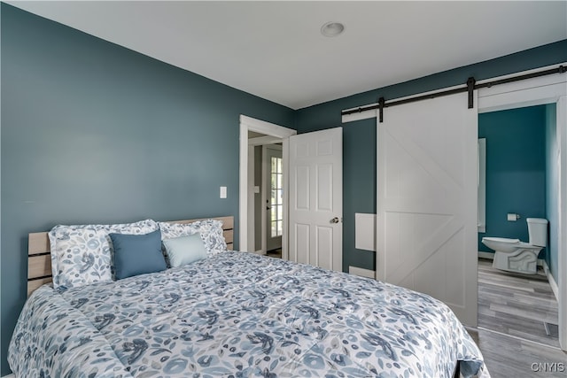 bedroom with light hardwood / wood-style floors and a barn door