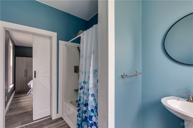 bathroom with hardwood / wood-style flooring, shower / bath combination with curtain, and sink