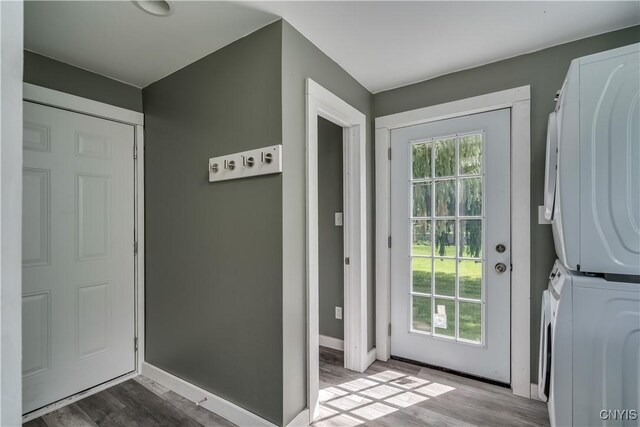 doorway to outside featuring stacked washer / drying machine, hardwood / wood-style flooring, and a healthy amount of sunlight