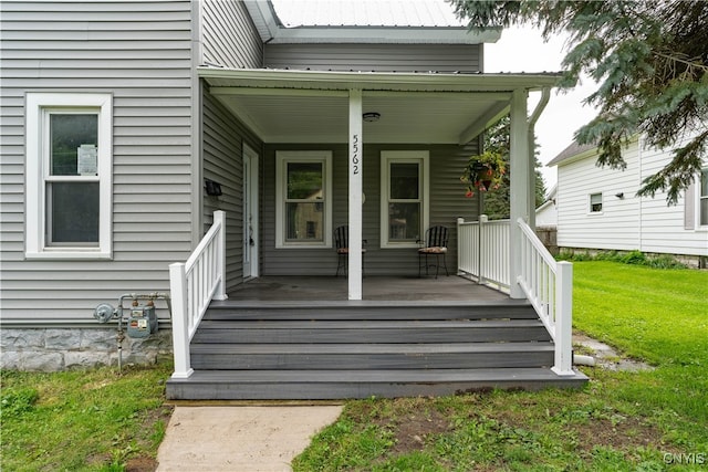 doorway to property featuring a porch and a lawn