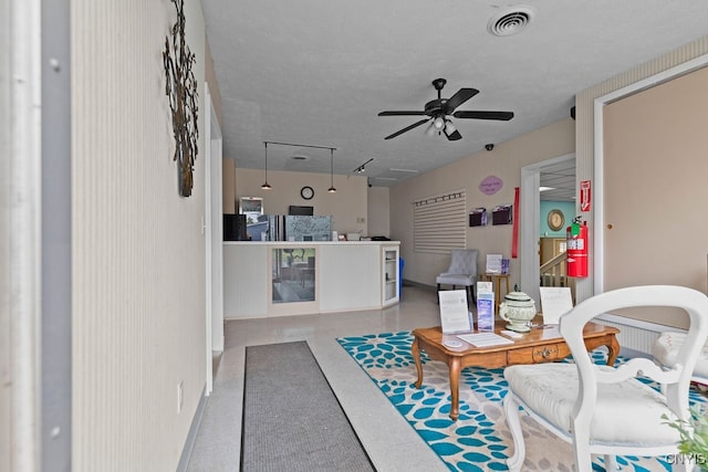 living room with a textured ceiling and ceiling fan