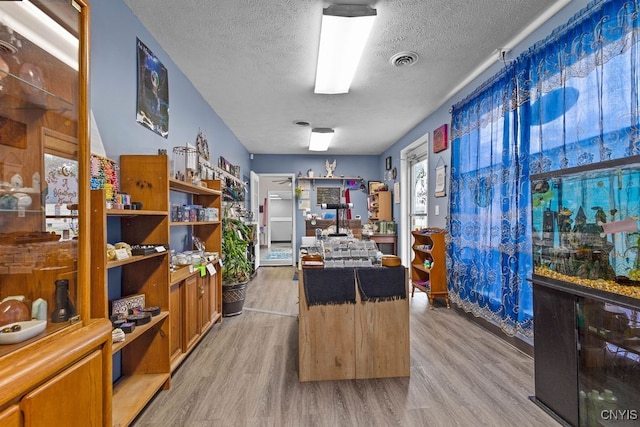 office with light wood-type flooring and a textured ceiling