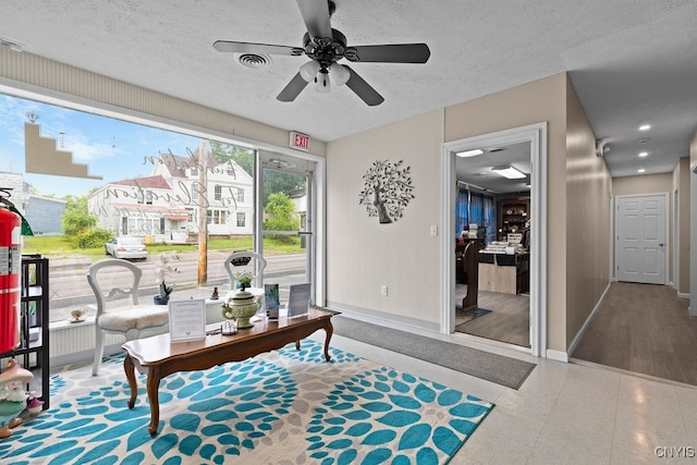 sitting room with ceiling fan, wood-type flooring, and a textured ceiling