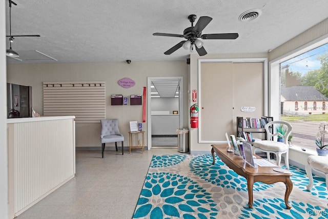 interior space featuring ceiling fan, a textured ceiling, and light tile patterned floors