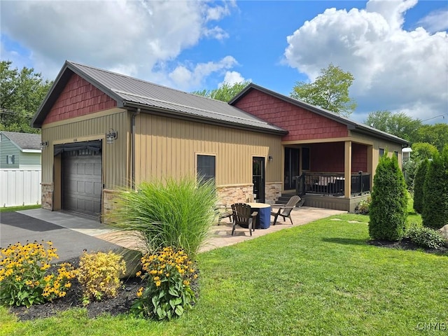 rear view of house featuring a patio area, a garage, and a yard