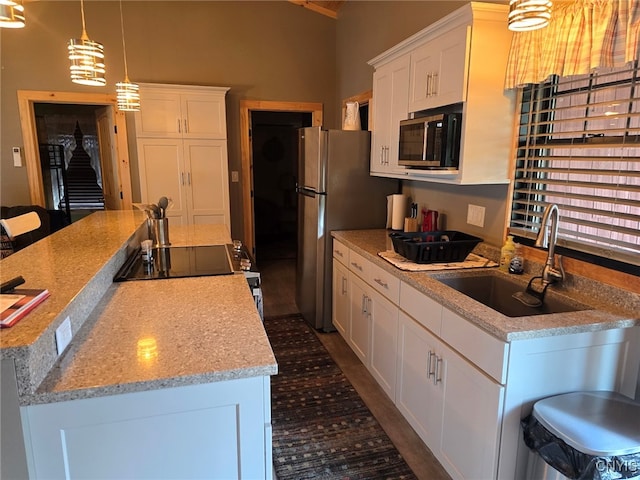 kitchen featuring sink, a center island, decorative light fixtures, appliances with stainless steel finishes, and white cabinets