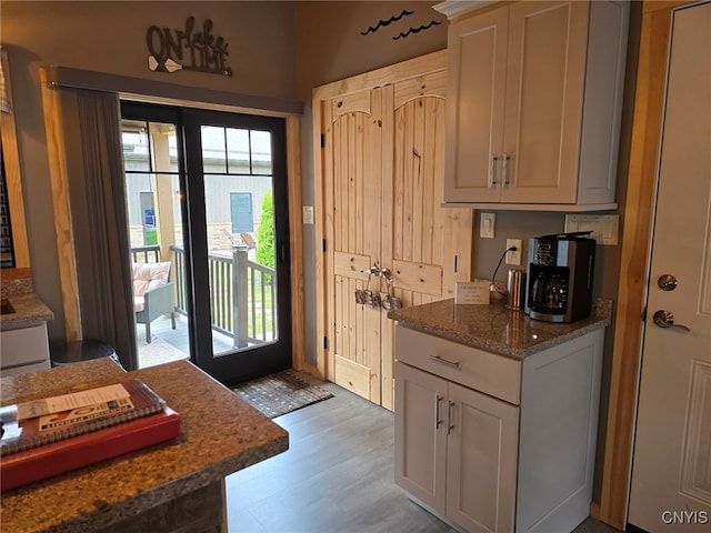 interior space with stone countertops, light hardwood / wood-style floors, and french doors