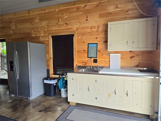 kitchen featuring sink, wooden walls, and stainless steel fridge