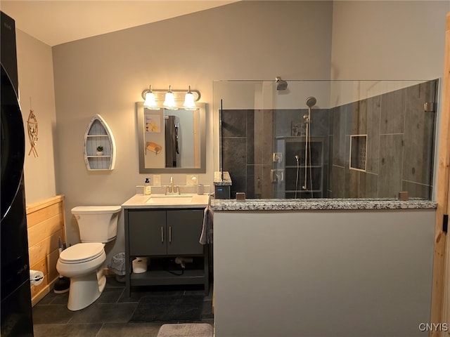 bathroom featuring vanity, tile patterned flooring, lofted ceiling, a tile shower, and toilet