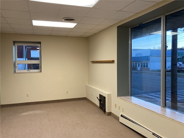 spare room featuring a paneled ceiling, light colored carpet, and baseboard heating