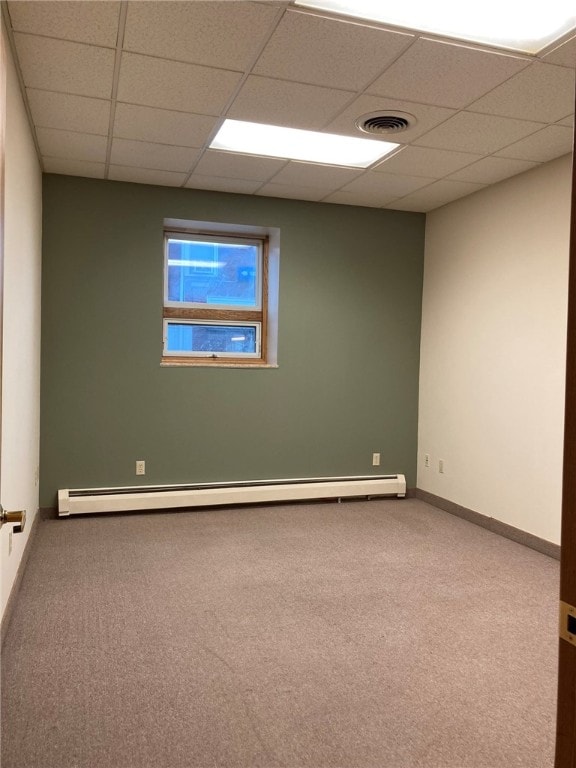 empty room with a drop ceiling, carpet, and a baseboard radiator