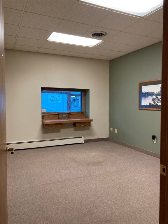 spare room with a paneled ceiling, a baseboard heating unit, and carpet floors