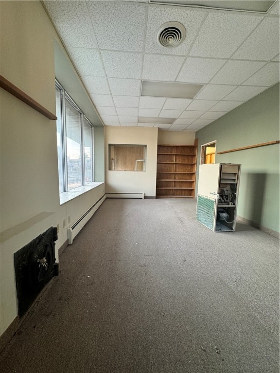 unfurnished living room with carpet, a baseboard heating unit, and a paneled ceiling