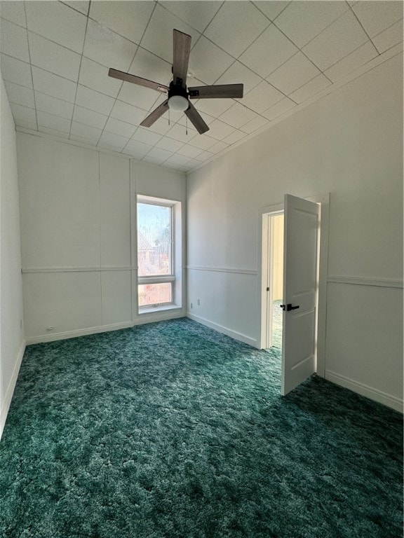 carpeted empty room with a drop ceiling and ceiling fan