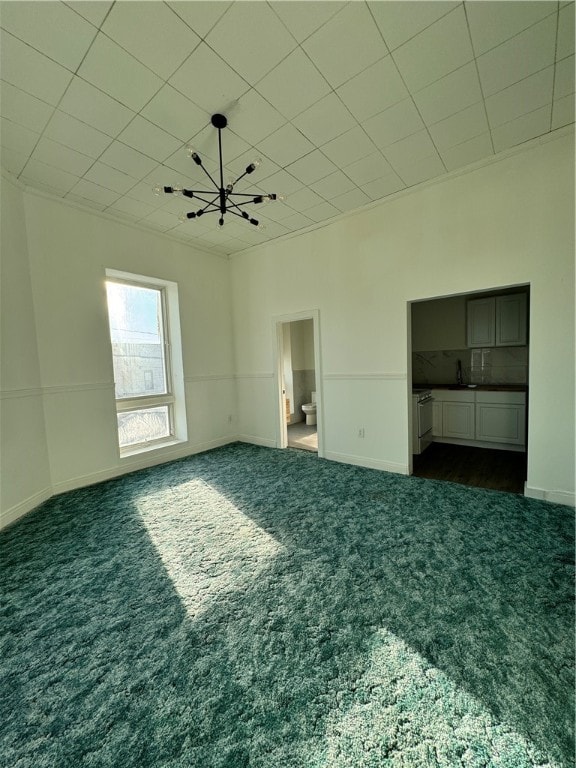 unfurnished bedroom featuring sink, an inviting chandelier, and dark colored carpet