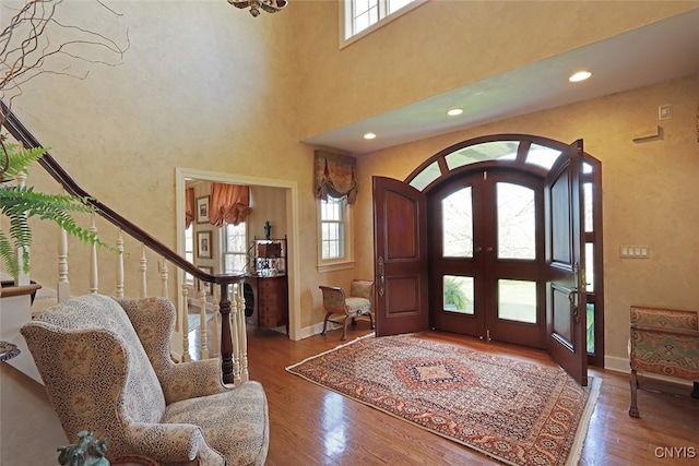 entrance foyer featuring a high ceiling, wood-type flooring, plenty of natural light, and french doors