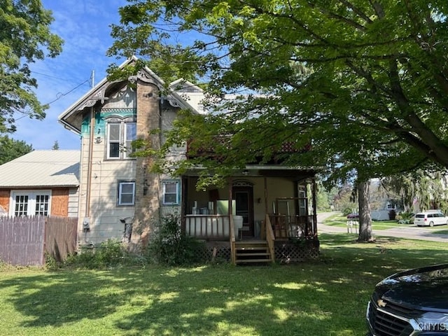 back of house featuring covered porch and a lawn