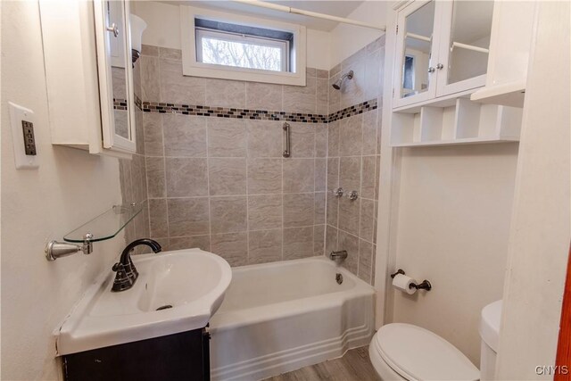 full bathroom with toilet, hardwood / wood-style floors, tiled shower / bath combo, and vanity