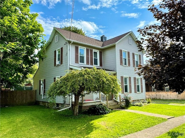 view of front facade featuring a chimney, fence, and a front lawn