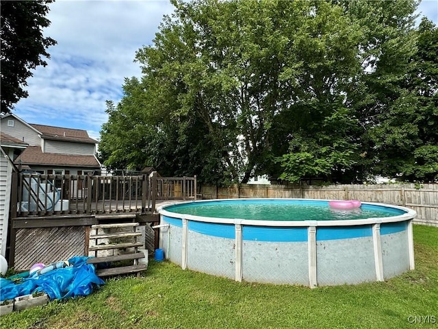 view of swimming pool featuring a fenced in pool, a fenced backyard, a lawn, and a wooden deck