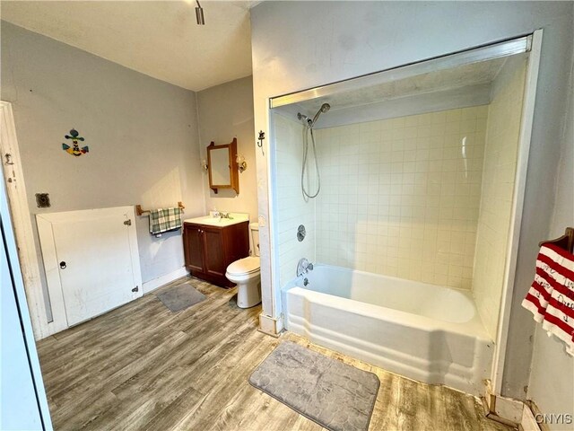 full bathroom with tiled shower / bath, vanity, toilet, and wood-type flooring