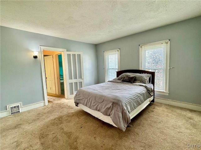 bedroom with baseboards, a textured ceiling, visible vents, and carpet flooring