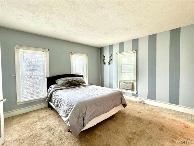 carpeted bedroom with multiple windows, a textured ceiling, and cooling unit