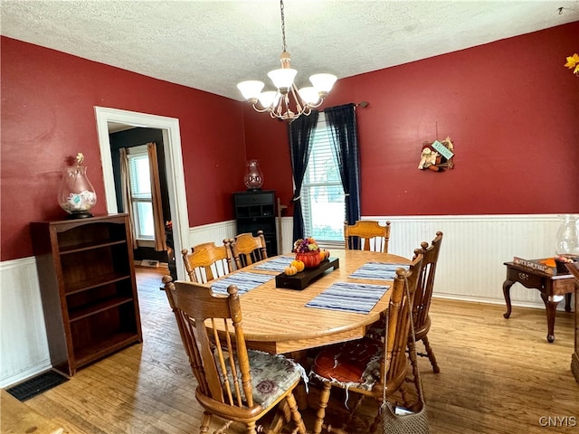 dining room with a textured ceiling, an inviting chandelier, and wood-type flooring