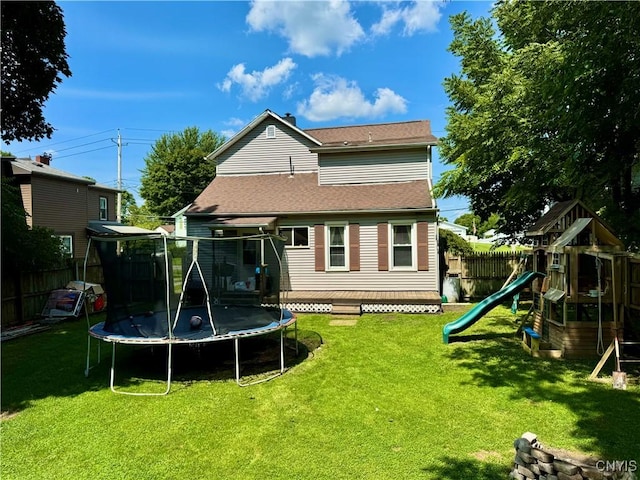 back of property with a trampoline, fence private yard, a playground, and a yard