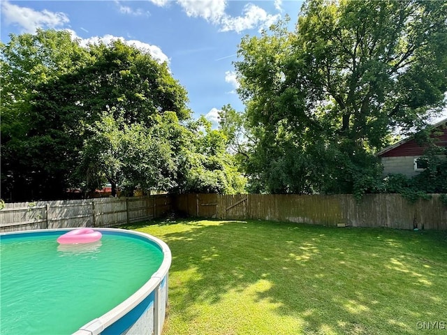 view of swimming pool with a yard and a fenced backyard