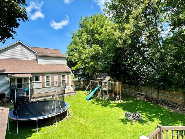 view of yard with a trampoline, a playground, and a wooden deck