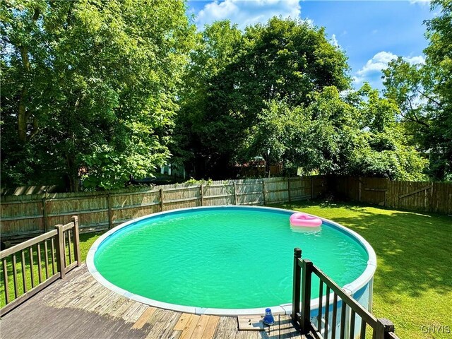 view of swimming pool with a wooden deck and a lawn