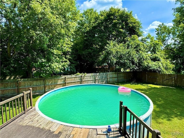 view of swimming pool featuring a fenced in pool, a fenced backyard, a lawn, and a wooden deck