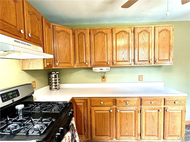 kitchen with gas range, under cabinet range hood, light countertops, and a ceiling fan