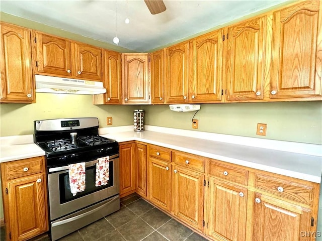 kitchen with light countertops, dark tile patterned floors, gas stove, and under cabinet range hood