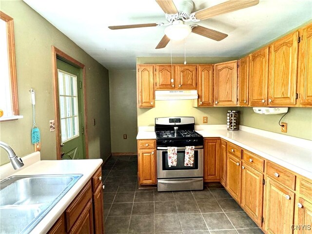 kitchen with stainless steel range with gas stovetop, dark tile patterned floors, sink, and ceiling fan