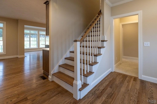 staircase with crown molding and hardwood / wood-style floors