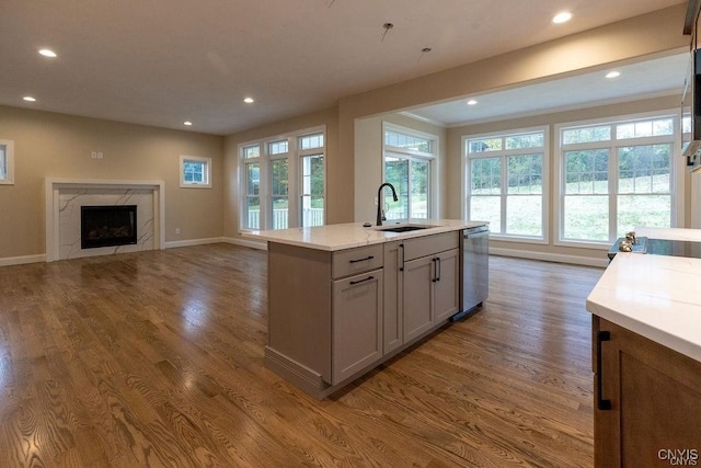 kitchen with sink, dark hardwood / wood-style flooring, dishwasher, gray cabinets, and a high end fireplace