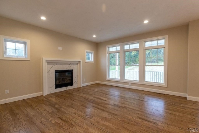 unfurnished living room featuring plenty of natural light, wood-type flooring, and a premium fireplace